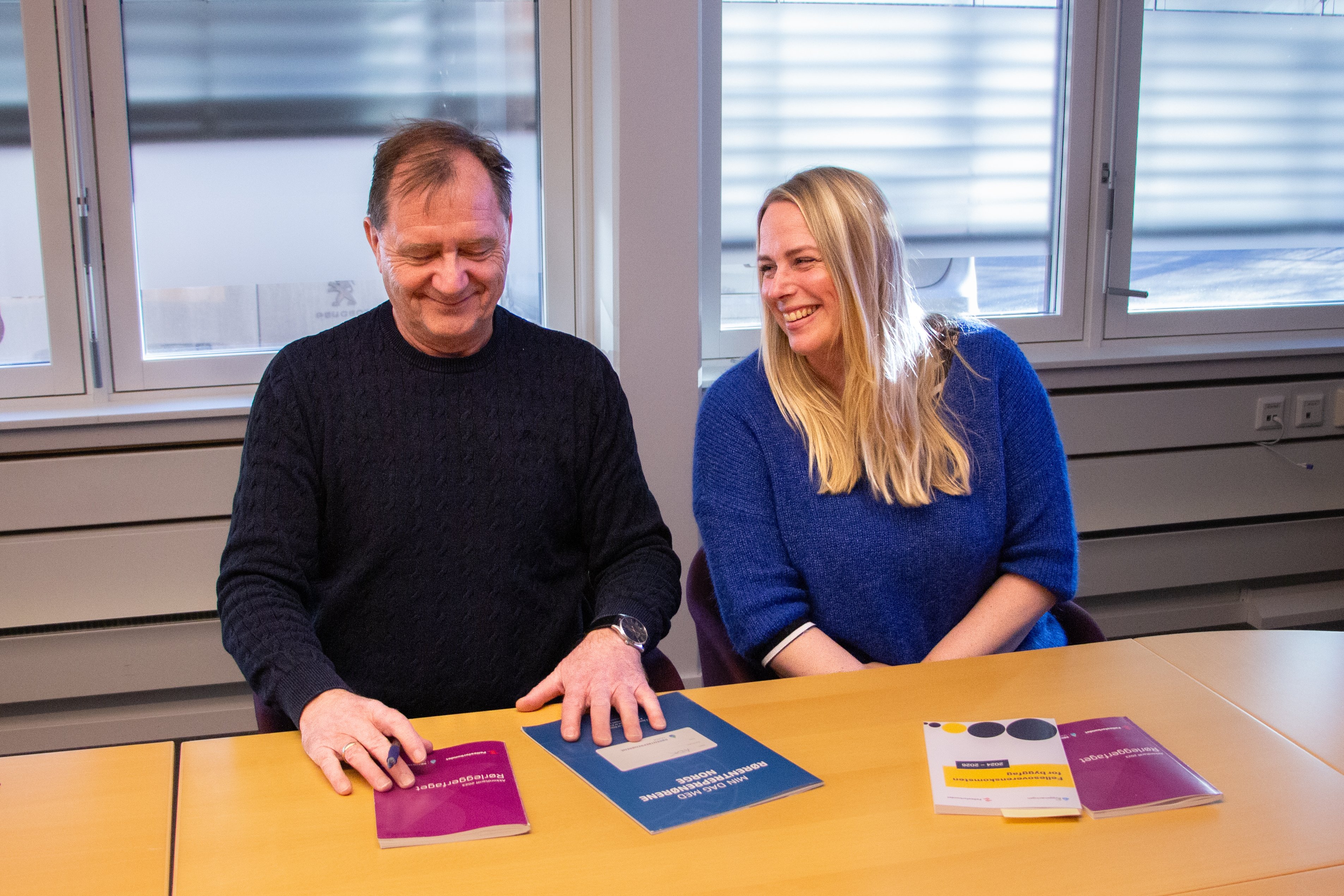 Bilde av Oddgeir Tobiassen og Iselin Abell Nilsen som smiler. De har akkordtariffen foran seg.